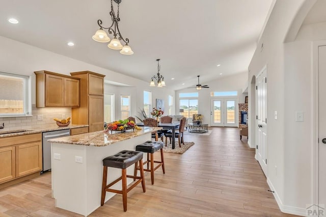 kitchen featuring tasteful backsplash, stainless steel dishwasher, open floor plan, a kitchen island, and a kitchen bar