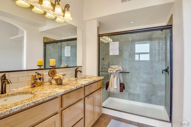 bathroom featuring a stall shower, a sink, and decorative backsplash