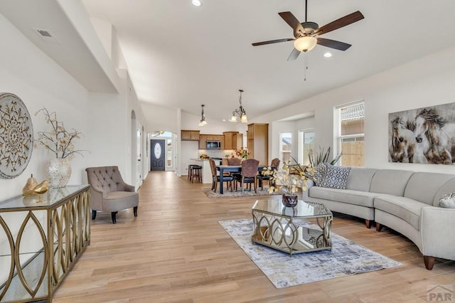 living area featuring arched walkways, ceiling fan, recessed lighting, visible vents, and light wood finished floors