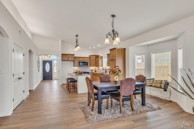 dining room featuring light wood-type flooring, baseboards, and arched walkways