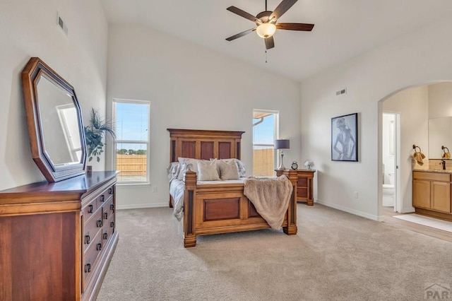 bedroom with arched walkways, light carpet, and multiple windows