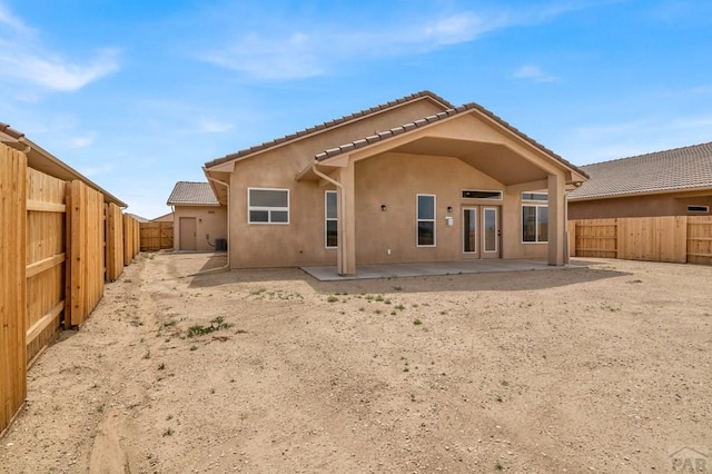 rear view of house with a fenced backyard, a patio, a tiled roof, and stucco siding