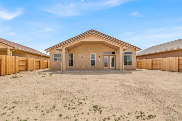 rear view of property featuring a fenced backyard, a patio, and stucco siding