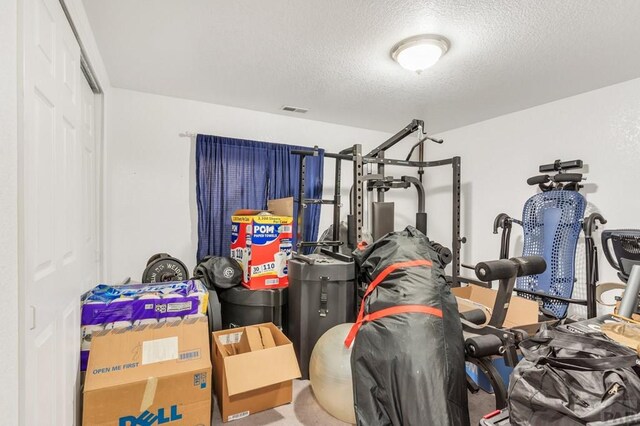 exercise area featuring visible vents and a textured ceiling