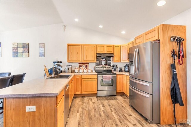 kitchen featuring appliances with stainless steel finishes, light countertops, a sink, and a peninsula