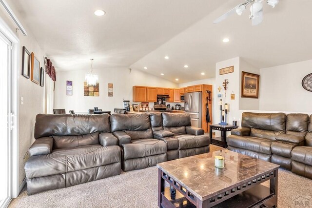 living area with lofted ceiling, recessed lighting, light carpet, and ceiling fan with notable chandelier