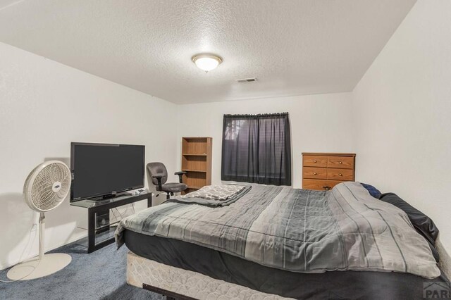 bedroom with carpet, visible vents, and a textured ceiling