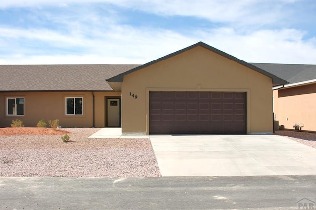 ranch-style house with a garage, driveway, and stucco siding