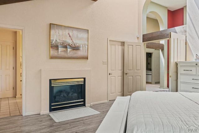 bedroom with baseboards, a fireplace with flush hearth, and light wood-style floors