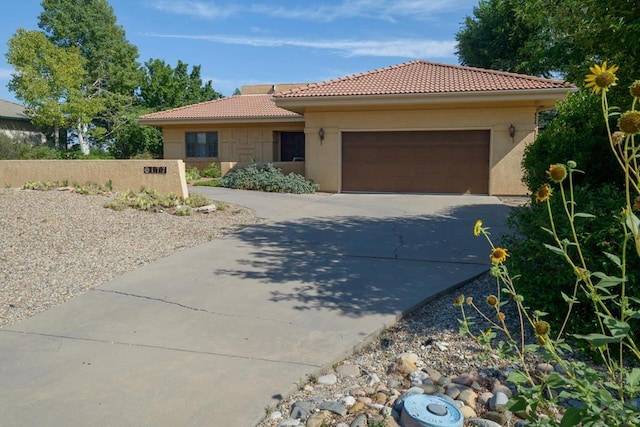 view of front of home featuring a garage, a tile roof, driveway, and stucco siding