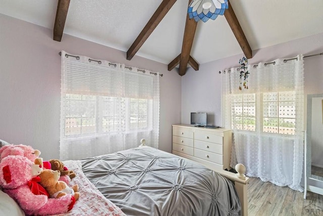 bedroom with lofted ceiling with beams and wood finished floors