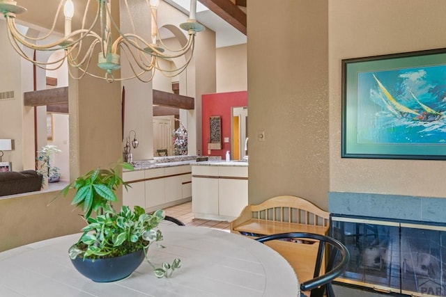 dining area with a high ceiling, visible vents, a notable chandelier, and a textured wall