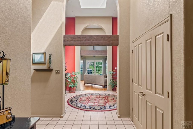 hallway featuring a textured wall and light tile patterned floors