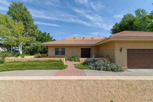 view of front of house with a garage, a tiled roof, and stucco siding