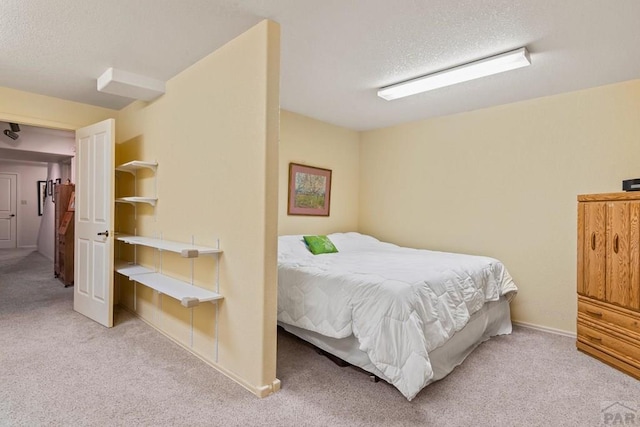 bedroom featuring light colored carpet, a textured ceiling, and baseboards