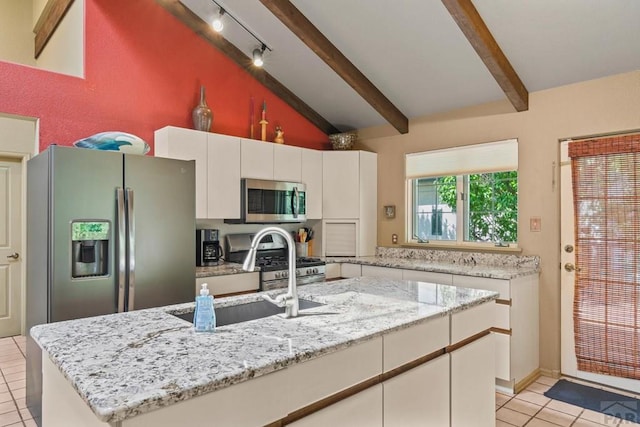 kitchen with lofted ceiling with beams, stainless steel appliances, a kitchen island, a sink, and white cabinetry