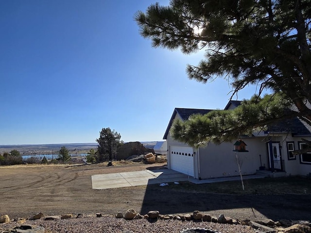 6190 Douglas Way, Colorado City, CO 81019 - view of side of home featuring an attached garage, stucco siding, driveway, and a water view