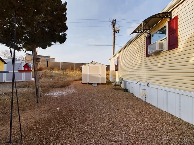 view of yard featuring a storage shed, fence, cooling unit, and an outbuilding