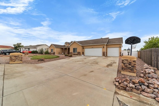 ranch-style house featuring a garage, fence, concrete driveway, and stucco siding