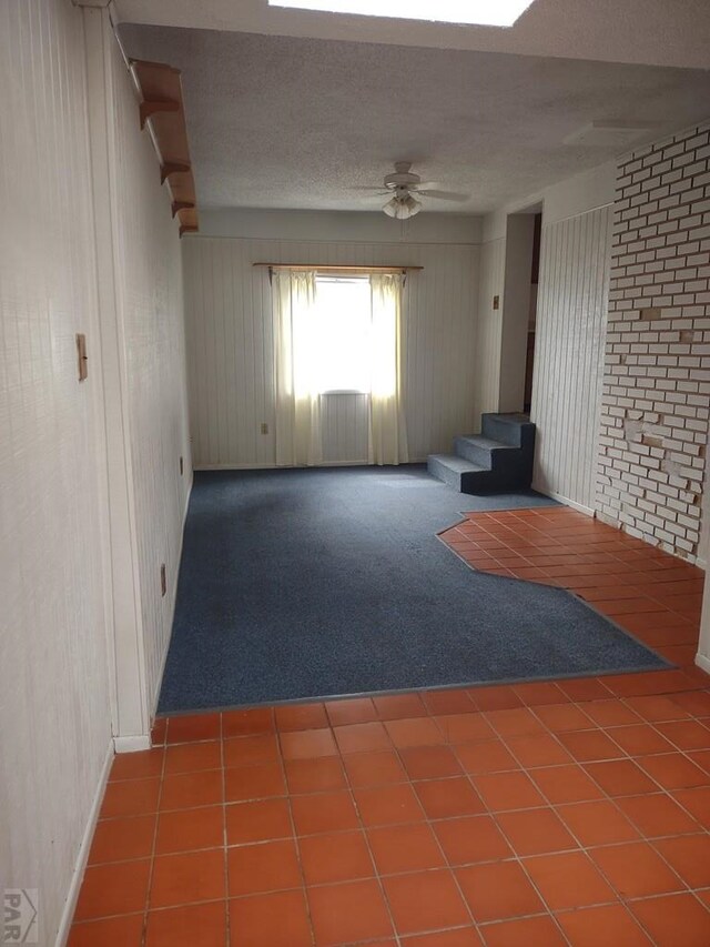 interior space with a ceiling fan, a textured ceiling, and tile patterned floors