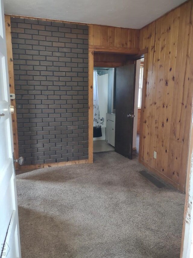 empty room with carpet floors and wooden walls