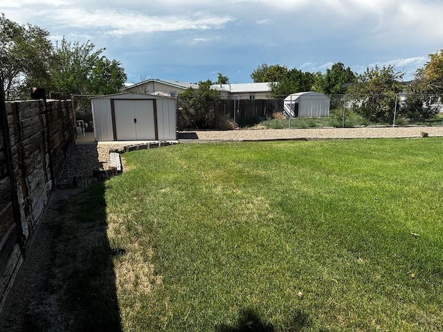 view of yard featuring a storage shed, a fenced backyard, and an outbuilding