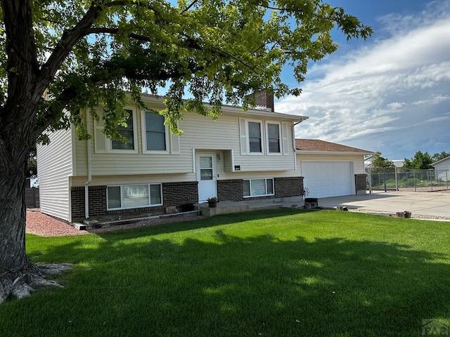 bi-level home featuring a garage, driveway, a chimney, and a front lawn