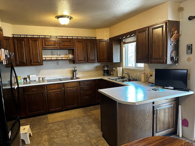 kitchen featuring a textured ceiling, a peninsula, light countertops, dark brown cabinets, and black appliances