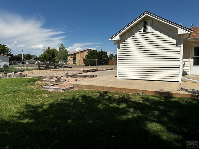 view of property exterior featuring a yard, a patio, fence, and a garden