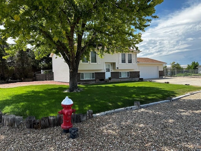 raised ranch with a front lawn, driveway, an attached garage, and fence