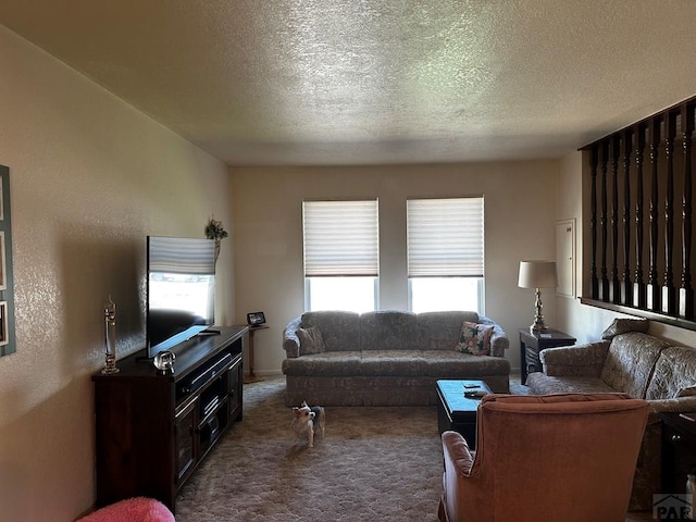 living room with a textured ceiling, a textured wall, and dark carpet