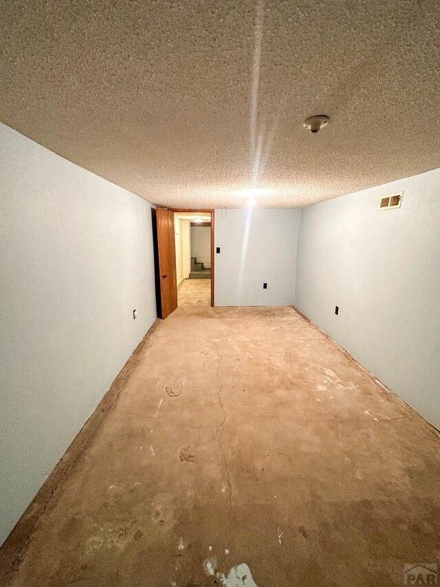 interior space with visible vents, a textured ceiling, and unfinished concrete floors