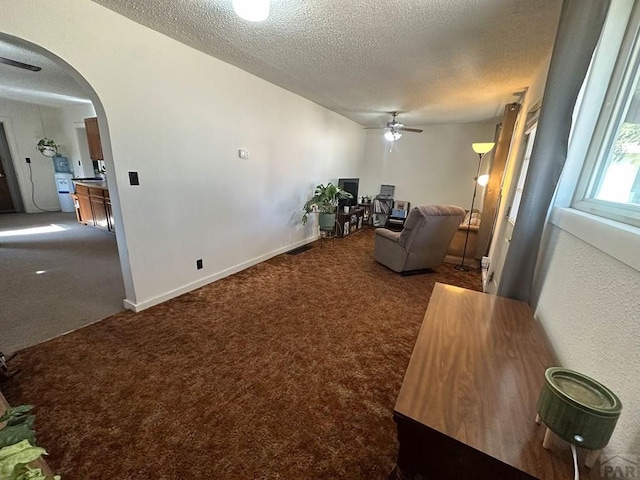 living room with arched walkways, dark colored carpet, and a textured ceiling