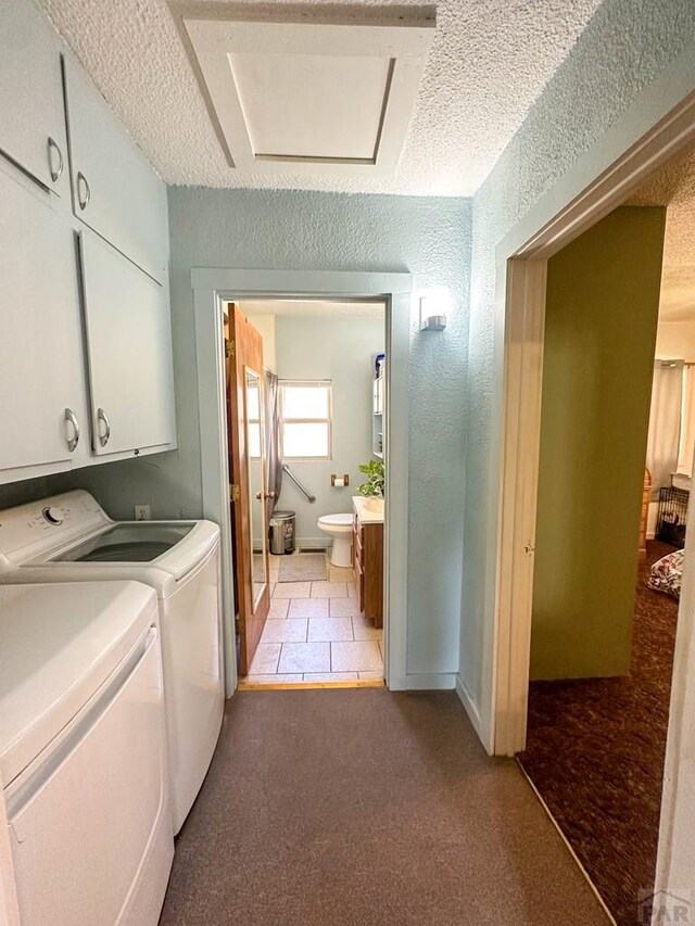 washroom with a textured ceiling, a textured wall, washing machine and dryer, and cabinet space