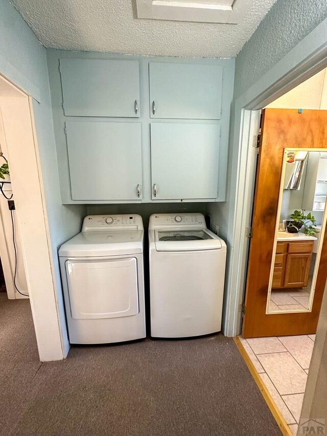 laundry room with light tile patterned floors, cabinet space, a textured ceiling, and separate washer and dryer