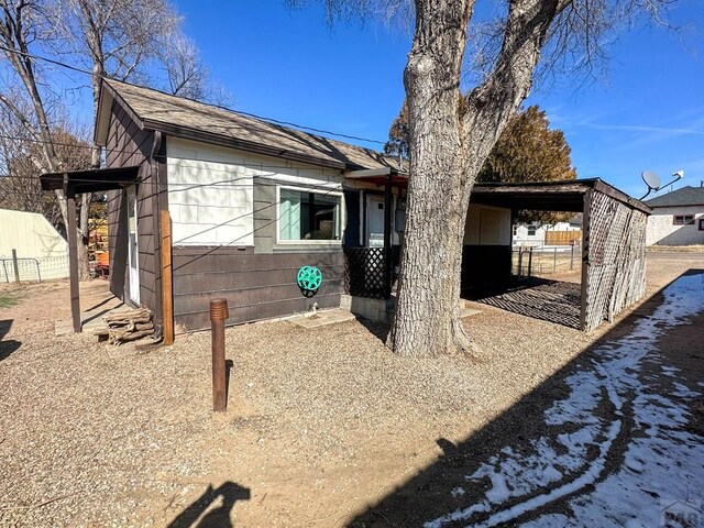 view of property exterior featuring a shingled roof and fence