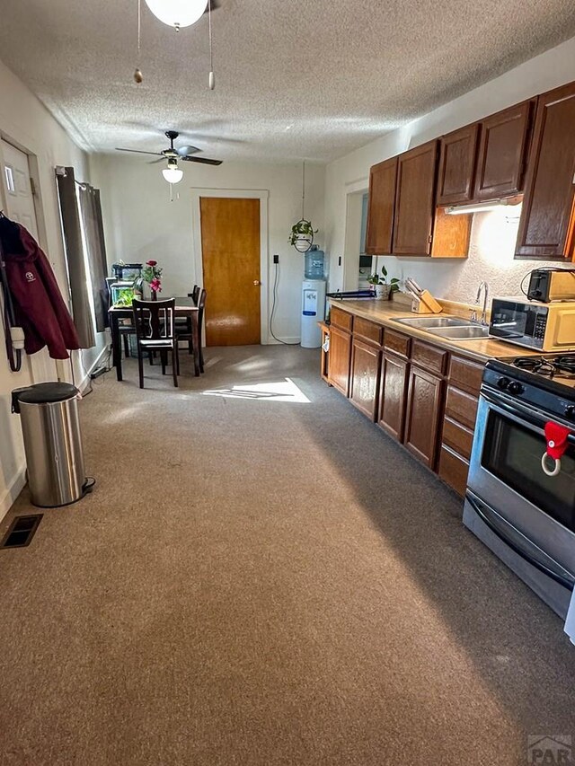 kitchen with visible vents, light colored carpet, gas range, light countertops, and a sink