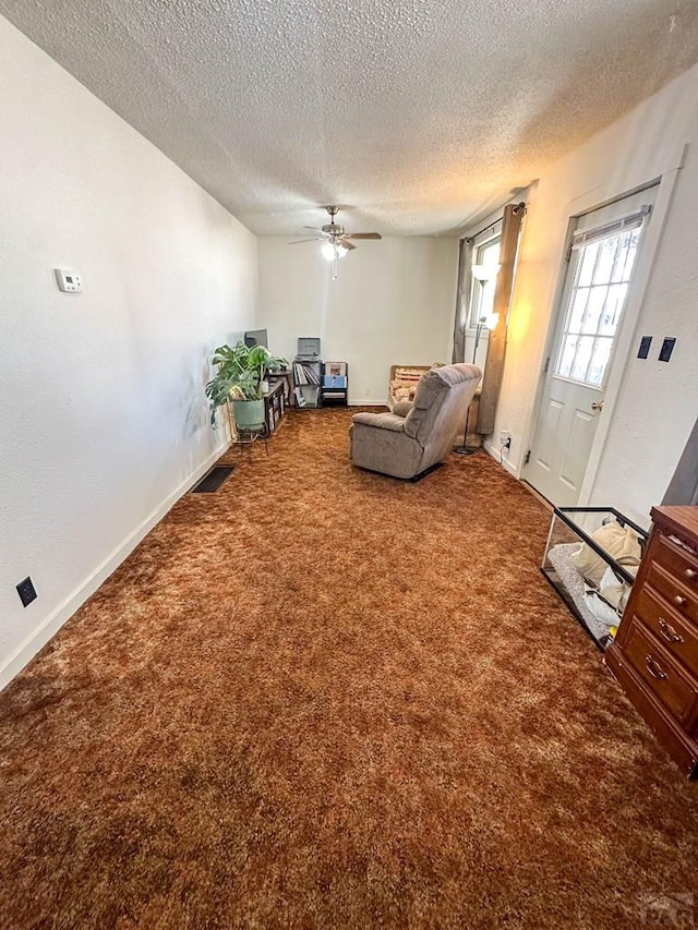 unfurnished living room with baseboards, visible vents, ceiling fan, a textured ceiling, and carpet flooring