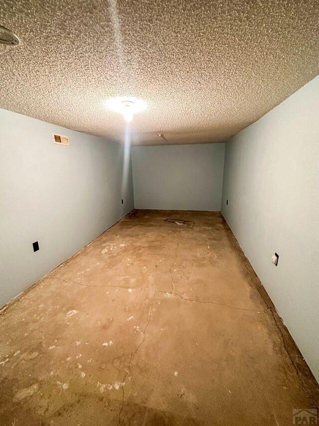 interior space featuring visible vents, unfinished concrete flooring, and a textured ceiling