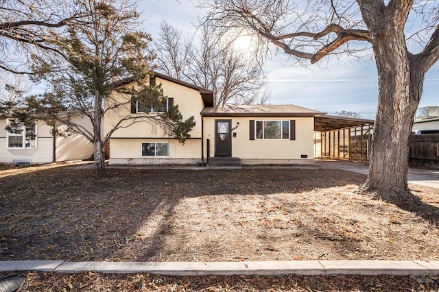 tri-level home featuring fence, an attached carport, and stucco siding