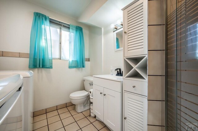 full bathroom with toilet, vanity, separate washer and dryer, and tile patterned floors