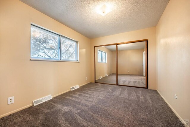 unfurnished bedroom featuring a textured ceiling, carpet flooring, and visible vents