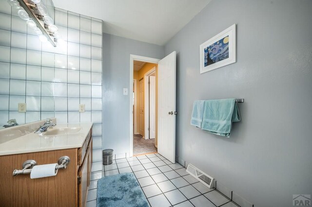 bathroom with visible vents, vanity, baseboards, and tile patterned floors