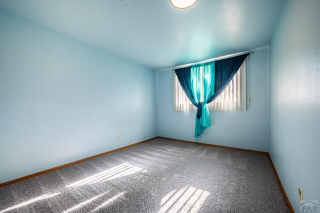 empty room featuring carpet and baseboards