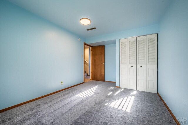 unfurnished bedroom featuring a closet, carpet, visible vents, and baseboards