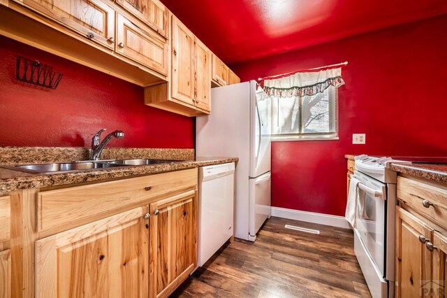 kitchen with white appliances, baseboards, dark countertops, dark wood-type flooring, and a sink