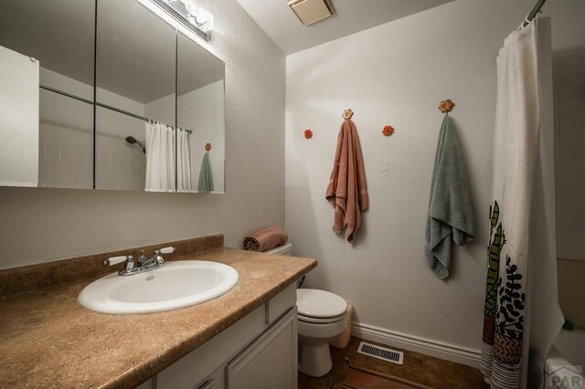 bathroom featuring toilet, vanity, visible vents, and baseboards