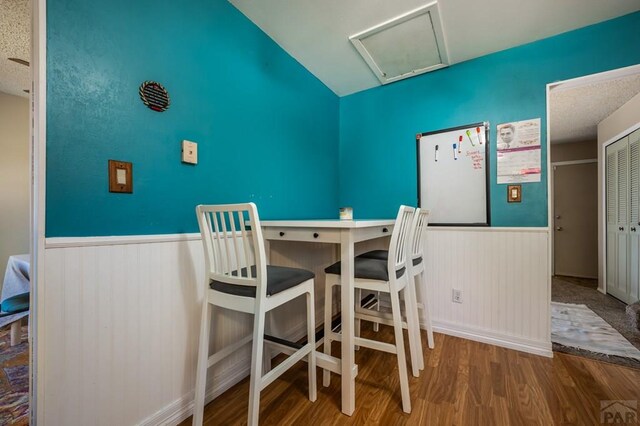 dining space featuring attic access, a wainscoted wall, and wood finished floors