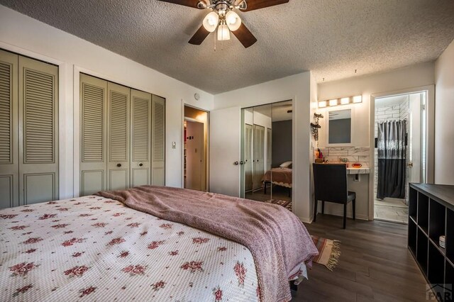 bedroom featuring a textured ceiling, a ceiling fan, dark wood-style flooring, and two closets