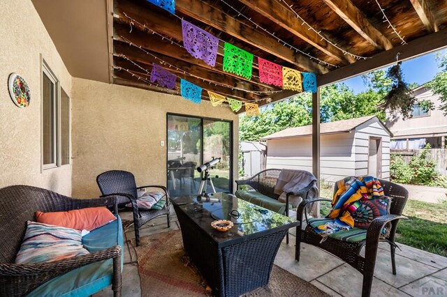 view of patio featuring an outbuilding, outdoor lounge area, fence, and a storage unit